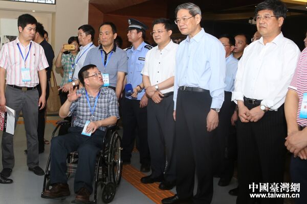 中共中央台办、国务院台办主任张志军与福建省残联副理事长杨小波(坐轮椅者)亲切交流。