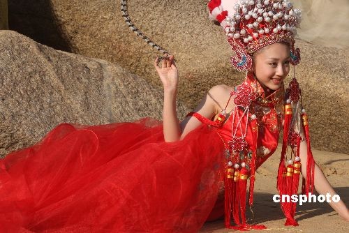 图为参赛佳丽在海边展示婚纱。